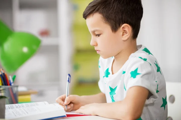 Primer plano de niño con la escritura de libros de texto en casa —  Fotos de Stock