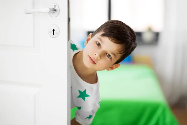 little boy behind door at home