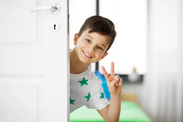 Boldog kisfiú otthon ajtó mögött mutatja a béke — Stock Fotó