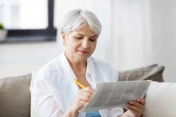 Mulher sênior marcando anúncio de jornal em casa — Fotografia de Stock