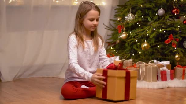 Feliz chica abriendo regalo de Navidad en casa — Vídeo de stock