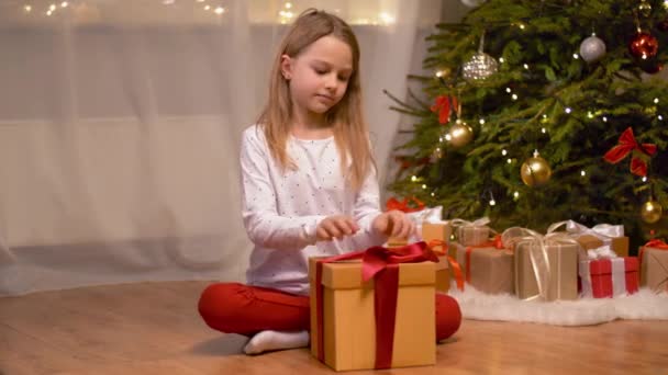 Menina feliz abrindo presente de Natal em casa — Vídeo de Stock