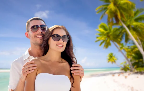 Счастливая пара в солнечных очках над тропическим пляжем — стоковое фото