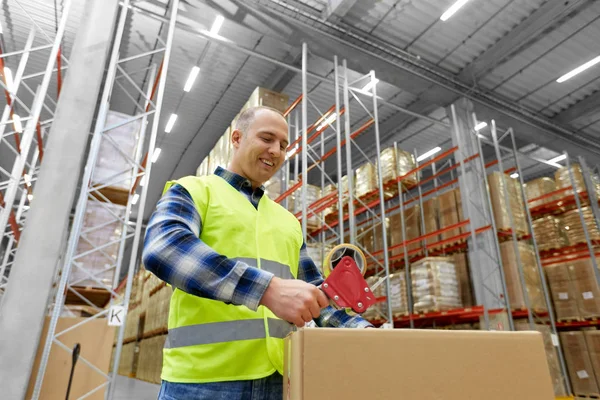 Warehouse worker packing parcel with scotch tape — Stock Photo, Image