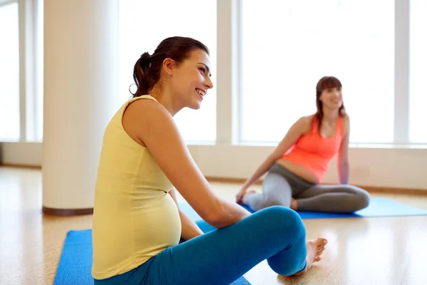 Glada gravida kvinnor sitter på mattor i gym — Stockfoto