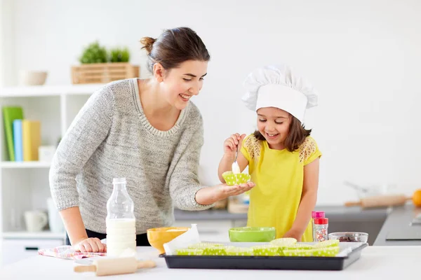 Mãe feliz e filha assar cupcakes em casa — Fotografia de Stock