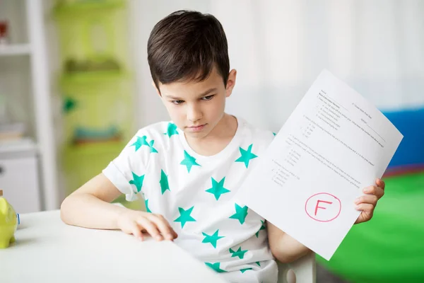 Menino triste segurando teste escolar com nota f — Fotografia de Stock