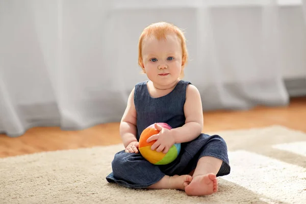 Härlig rödhårig flicka med leksak boll hemma — Stockfoto