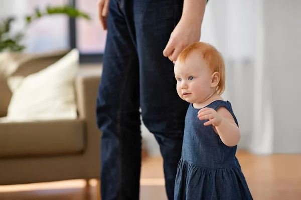 Bebé niña caminando con padre ayuda en casa — Foto de Stock