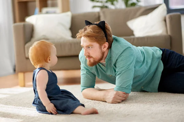 Father wearing cat ears headband playing with baby — Stock Photo, Image