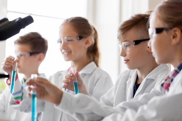 Niños con tubos de ensayo que estudian química en la escuela — Foto de Stock