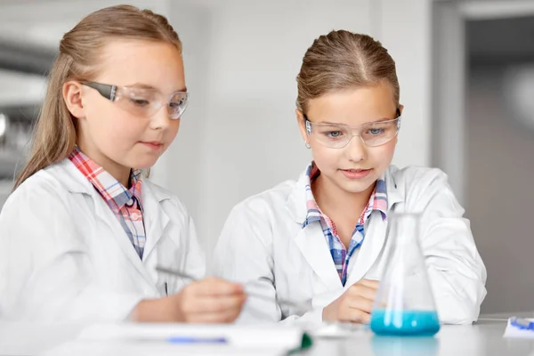 Девочки с пробиркой изучают химию в школе — стоковое фото