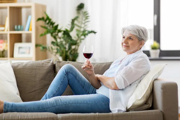 Senior woman with glass of red wine at home — Stock Photo, Image