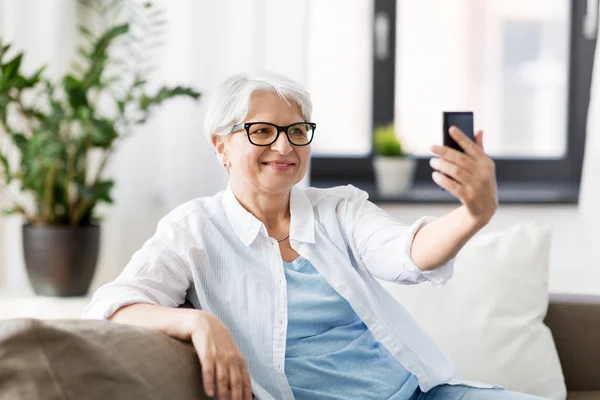 Mujer mayor tomando selfie por teléfono inteligente en casa — Foto de Stock