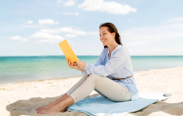 Heureuse femme souriante lecture livre sur la plage d'été — Photo