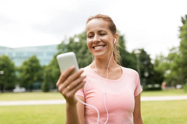 Kvinna som lyssnar på musik på smartphone på park — Stockfoto