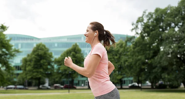 Woman with earphones running at park — Stock Photo, Image