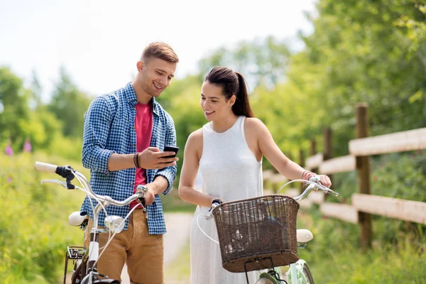 Casal com bicicletas e smartphone no verão — Fotografia de Stock