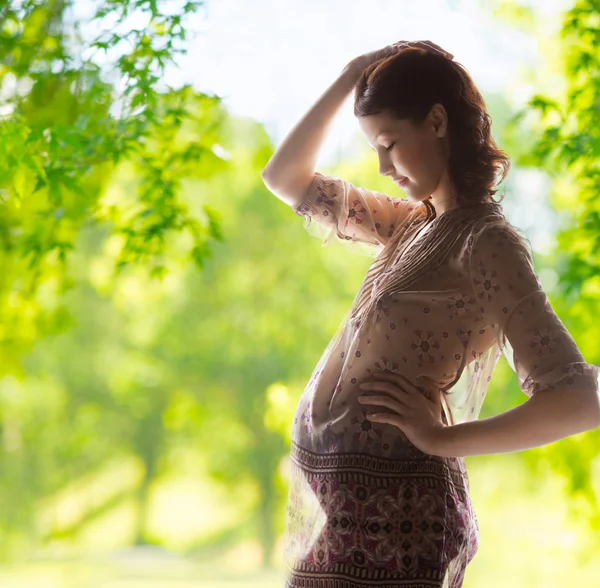 Mujer embarazada sobre fondo verde natural — Foto de Stock