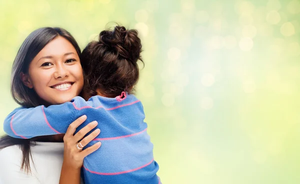 Gelukkig moeder en dochter knuffelen over groen — Stockfoto