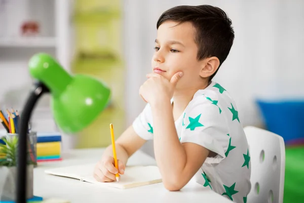 Mały chłopiec, w piśmie do notebooka w domu — Zdjęcie stockowe