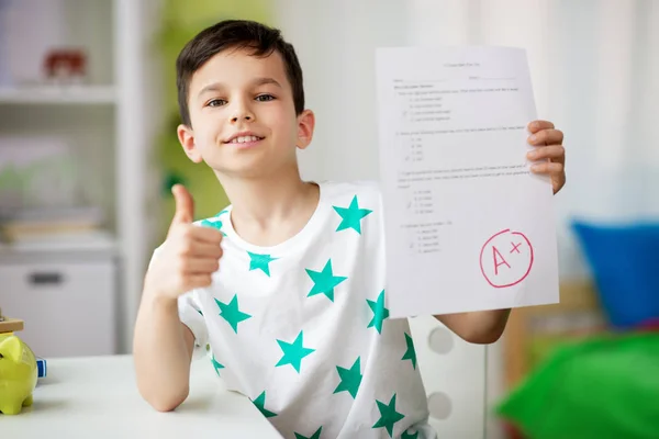 Happy smiling boy holding school test with a grade — Stock Photo, Image