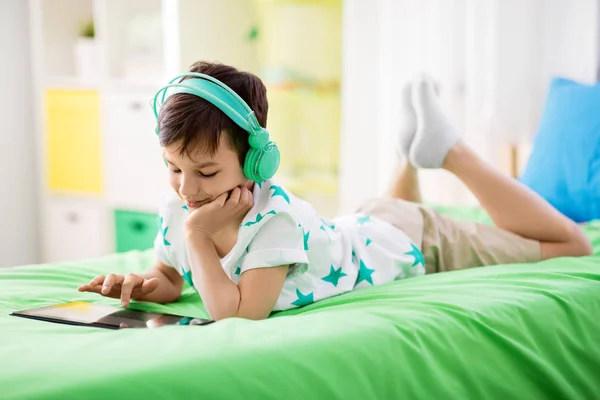 Leende pojke med TabletPC och hörlurar hemma — Stockfoto