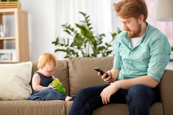 Otec s smartphone a baby hrát doma — Stock fotografie