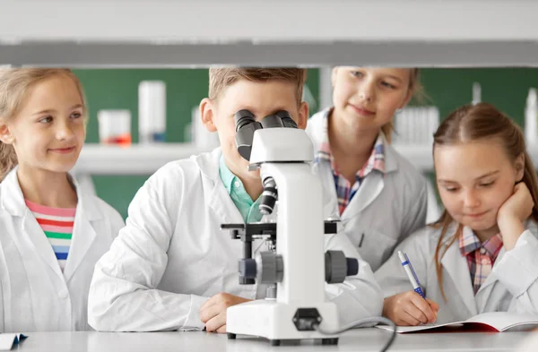 Niños o estudiantes con biología de microscopio en la escuela —  Fotos de Stock