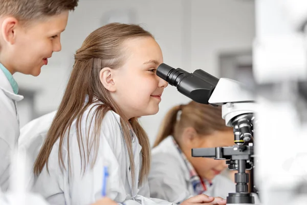 Дети или студенты с микроскопом биологии в школе — стоковое фото