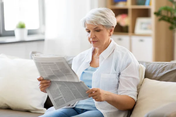 Mulher sênior ler jornal em casa — Fotografia de Stock