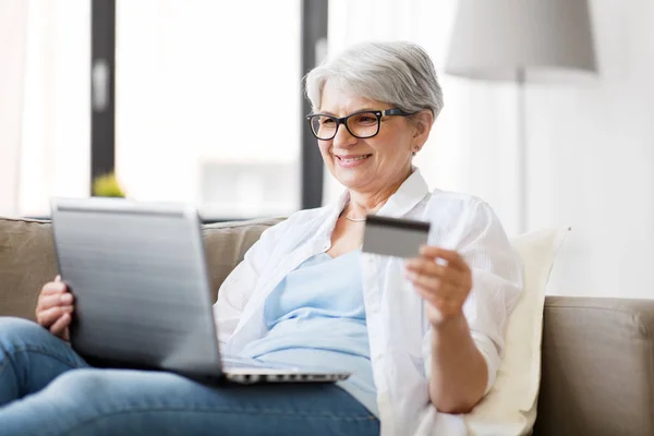 Oudere vrouw met laptop en creditcard thuis — Stockfoto