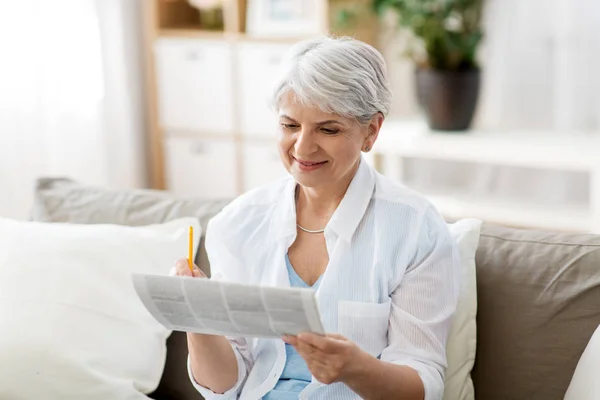 Senior kobieta oznakowanie gazecie reklama w domu — Zdjęcie stockowe