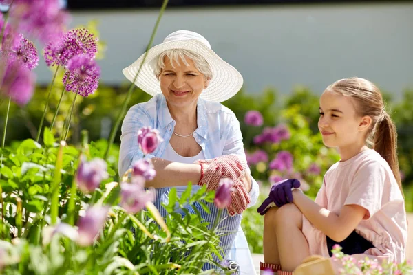 Mormor och flicka med blommor på sommaren garden — Stockfoto