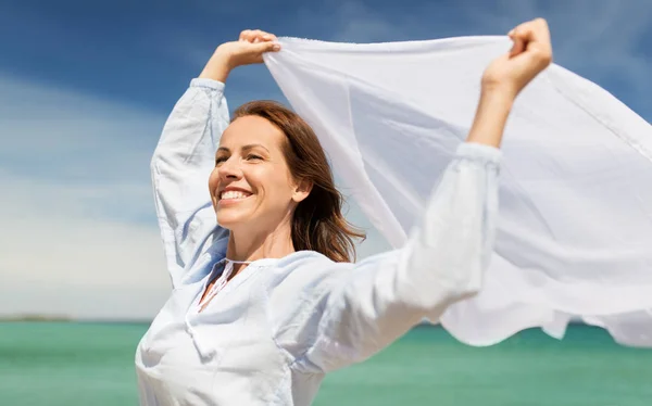 Glückliche Frau mit Tuch, das im Wind am Strand weht — Stockfoto