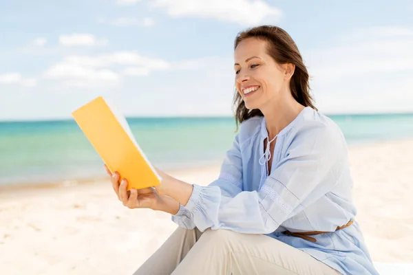 快乐微笑的妇女在夏天海滩读书书 — 图库照片