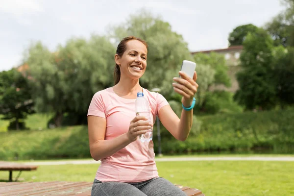 Donna con smartphone, acqua e fitness tracker — Foto Stock