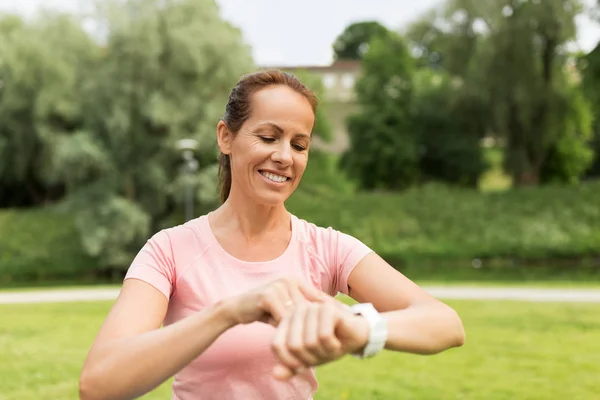 Kadın parkta akıllı saat ya da fitness izci ile — Stok fotoğraf