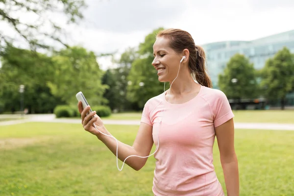 Женщина слушает музыку на смартфоне в парке — стоковое фото