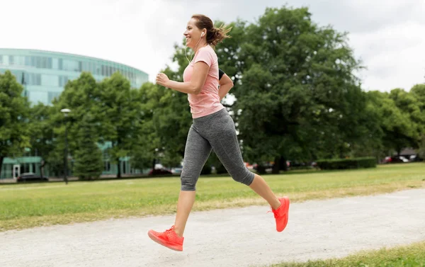 ผู้หญิงที่มีหูฟังวิ่งที่สวนสาธารณะ — ภาพถ่ายสต็อก