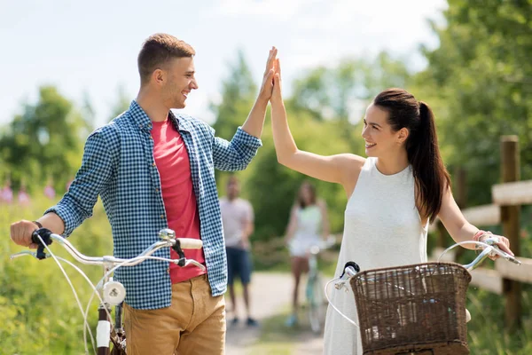 Par med cyklar att göra high five på sommaren — Stockfoto