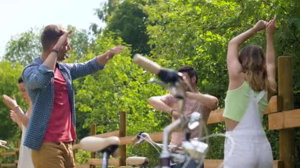 Amigos felices con bicicletas bailando en el parque de verano — Vídeo de stock