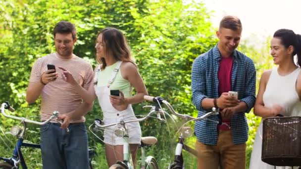 Amigos con bicicletas y smartphones en el parque — Vídeo de stock