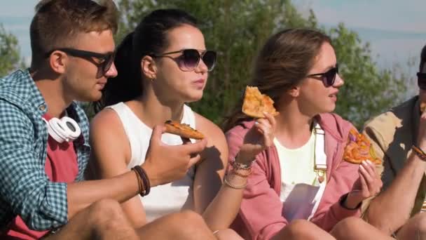 Vrienden eten pizza op picknick in het park van de zomer — Stockvideo