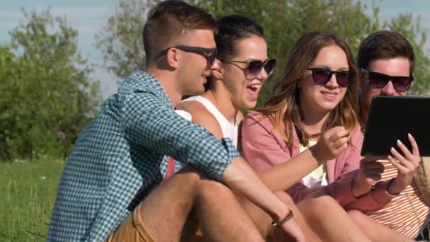 Lachende vrienden met de tablet pc in zomer park — Stockvideo