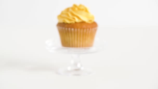 Кекс с желтой глазурью на стеклянной подставке — стоковое видео
