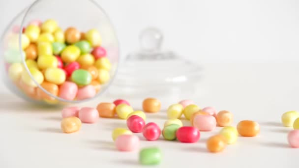 Primer plano de gotas de caramelo dispersas y frasco en la mesa — Vídeo de stock