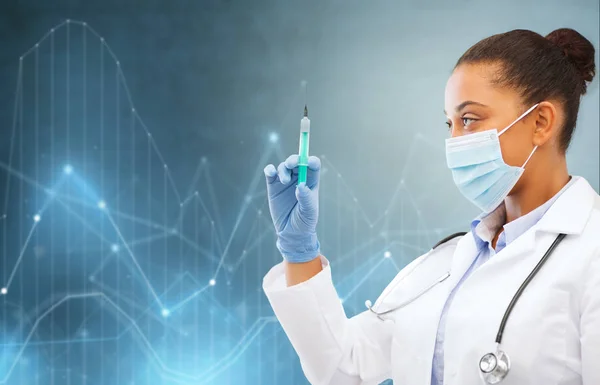 African female doctor with syringe over diagrams — Stock Photo, Image