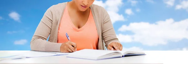 Estudante menina com livro escrito para notebook — Fotografia de Stock