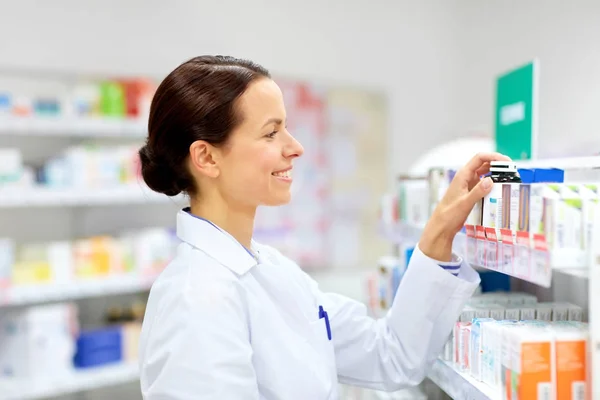 Boticario femenino feliz con la droga en la farmacia —  Fotos de Stock